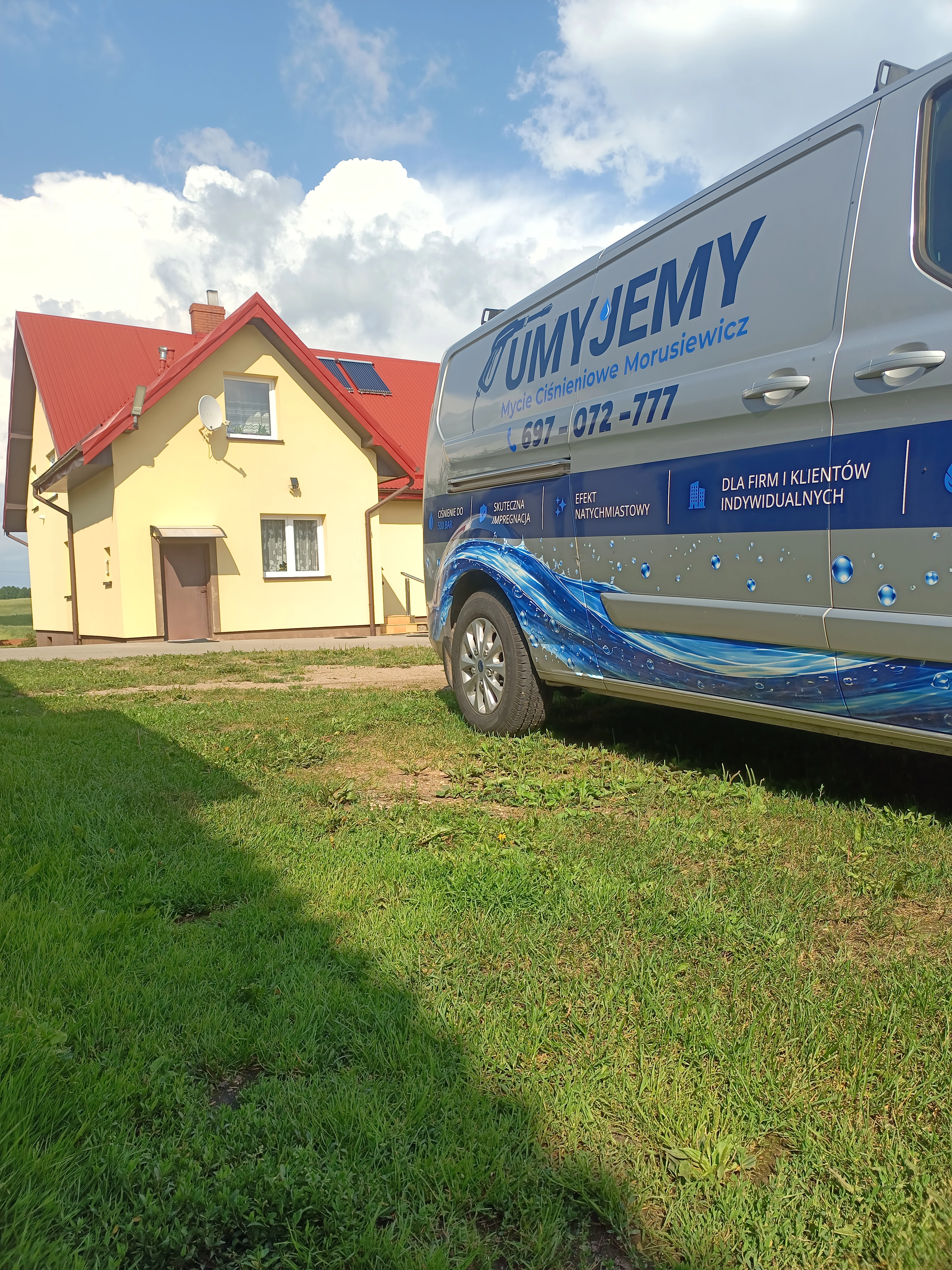 Bus UMYJEMY przed umytym domem z czerwonym dachem